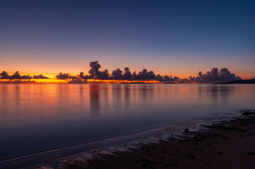 Fototapeta premium Serene dawn with blue, lilac, yellow and orange colors painting the sky and the sea with the same colors on Nakano beach. Iriomote Island.
