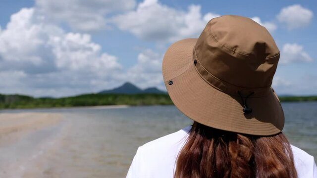Blurred rear view of a woman with hat looking at the sea with blue sky 