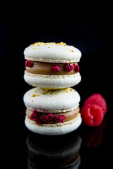  Zwei Stück Macorons Pistazie - Himbeere.  Schwarzer Hintergrund - gespiegelt.