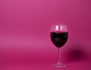 a glass of red wine on a bright pink background close-up, isolated object. suitable for advertising wine restaurant, wine list of wine factory products. copy space