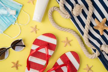 Top view photo of sanitizer medical masks cream bottle beach bag striped flip-flops sunglasses and starfishes on isolated pastel yellow background