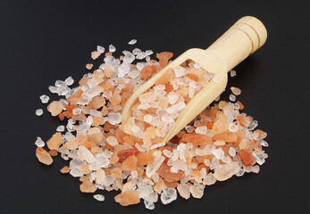 Himalayan rock salt in wooden scoop on black table	