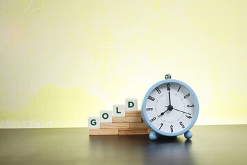 Block letters on Gold on the stacked wooden blocks with an alarm clock at the side 