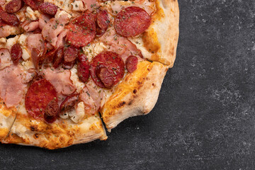 Four meat pizza on a dark concrete background