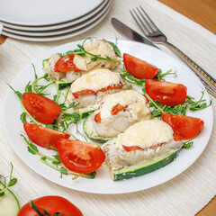 Baked fillet of codfish served with zucchini and tomatoes. Healthy food