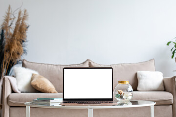 Laptop with blank white screen on the desk, mock up. Personal laptop computer on the table in living room with modern interior. Home work concept