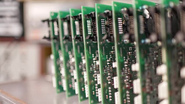 Slider shot video of electronic digital PCB boards on workshop table. Metal components and microcircuits lie on metal compartments during the production of cases of future powerful supercomputers