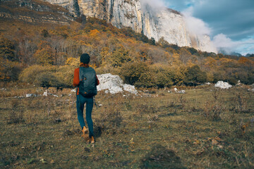 Fototapeta premium woman in jeans boots and a sweater with a backpack are resting in the autumn in the mountains in nature