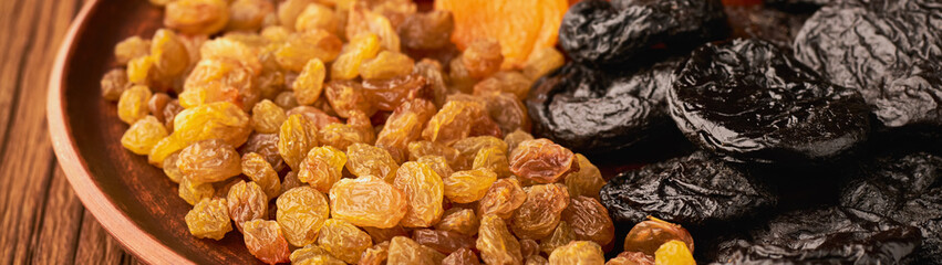 Assortment of dried fruits and raisins and apricots with plums in a plate banner