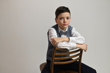Portrait of a teenager boy sitting on a chair on a white background in the studio