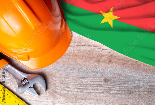 Burkina faso flag with different construction tools on wood background, with copy space for text. Happy Labor day concept.