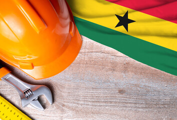 Ghana flag with different construction tools on wood background, with copy space for text. Happy Labor day concept.