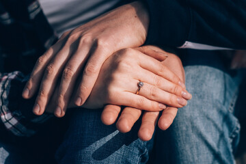 man holds the hand of his beloved with a wedding ring on his finger 