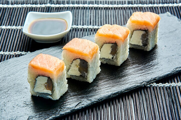 Philadelphia classic roll with prawns on a dark stone on a board. Japanese sushi.