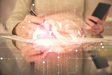 Double exposure of brain sketch hologram and woman holding and using a mobile device.