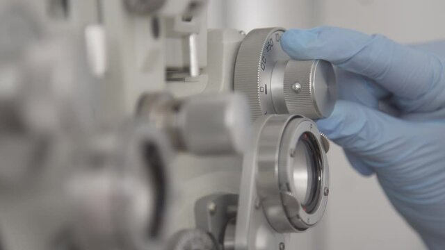 Close up the ophthalmologist fine-tunes the optics of the Phoropter equipment.