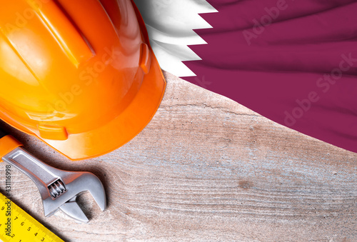 Qatar flag with different construction tools on wood background, with copy space for text. Happy Labor day concept.