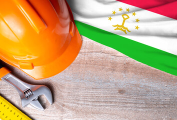 Tajikistan flag with different construction tools on wood background, with copy space for text. Happy Labor day concept.