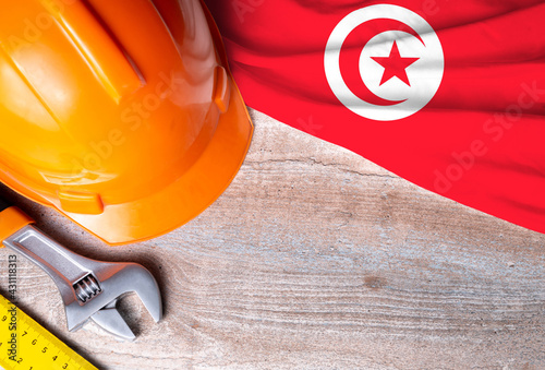 Tunisia flag with different construction tools on wood background, with copy space for text. Happy Labor day concept.
