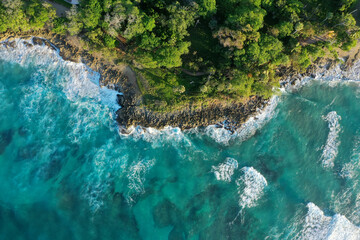 Aerial shot of cliffs covered in greenery surrounded by the sea under the sunlight © Angel Bracho/Wirestock