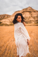 Young brunette Caucasian model in a white dress and a black bikini enjoying in the beautiful desert one summer afternoon