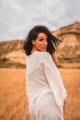Fototapeta premium Portrait of a young brunette Caucasian model in a white dress and a black bikini enjoying in the beautiful desert one summer afternoon