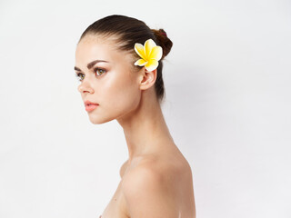 Fototapeta na wymiar pretty woman with bare shoulders yellow flower behind ear clear skin charm