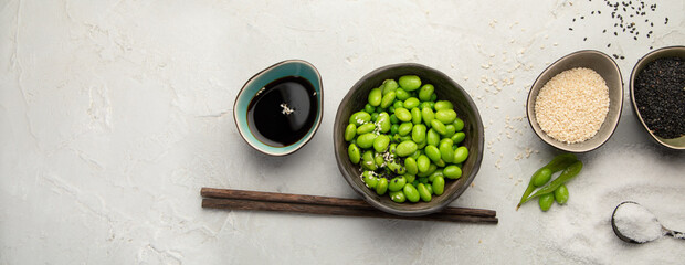 Obraz na płótnie Canvas Raw edamame soya beans with salt and sauce on light gray background.
