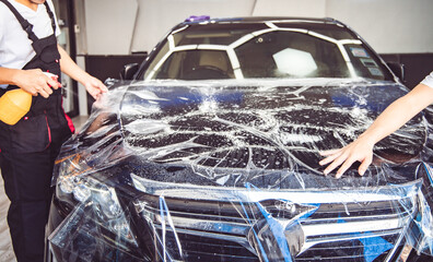 Paint protection film installation on door panel of luxury sports car. PPF is polyurethane film...