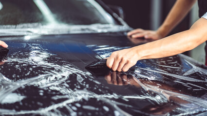 Paint protection film installation on door panel of luxury sports car. PPF is polyurethane film...