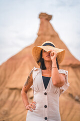 Sensual gazes from a brunette Caucasian girl in an explorer outfit with a white dress in a desert on a cloudy afternoon