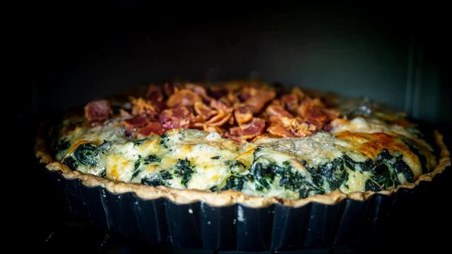 Time lapse of spinach quiche in oven. Homemade french quiche with cheese, spinach, egg and bacon bake in oven in time lapse.