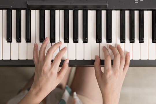 Top view of a girl's hand playing on a piano