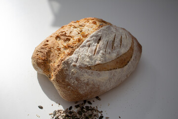Seeded Bread, bread making, home made bread, sourdough, natural yeast bread, rustic bread, home baking, sun over a loaf of bread on a white table with mixed seeds