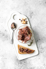Beef stew in a glass bowl and on toast on a light gray table top view	