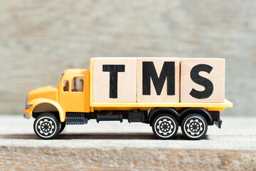 Toy truck hold alphabet letter block in word TMS (Abbreviation of Transportation management system...