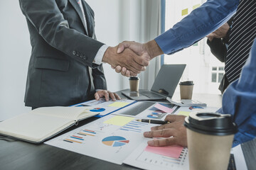 handshake after businesswomen and businessmen team meeting to plan strategies to increase business income. Have a brainstorming finance graph analysis and discussing for the new target success