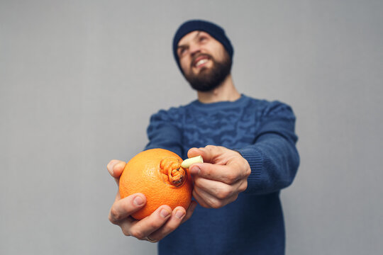 angry bearded man inserts into suppository in orange, concept of hemorrhoids or proctological diseases.