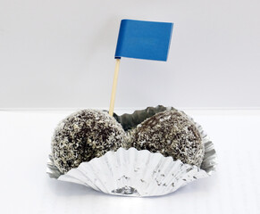 Two chocolates ball in foil cup decorate with blue flag.