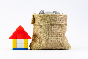 Front close up shot of a toy house made with Brickss and jute bag of coins in home loan and saving...