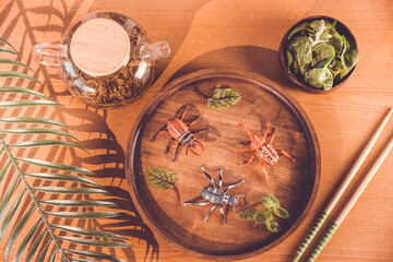 Fototapeta na wymiar still life in Japanese style with chopsticks and teapot. beetles on a plate. still life with toy beetles and palm leaves