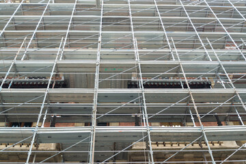 Perspective of a scaffolding structure on the facade of an ancient building in the centre of Milan, Italy.