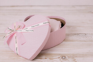 Gift pink box in the shape of a heart on a wooden light floor. A gift for girlfriend, mom or daughter