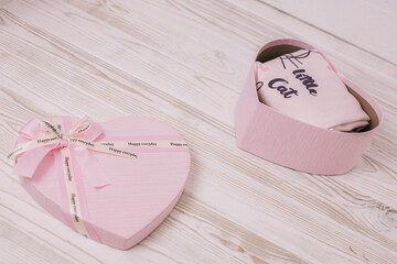 Gift pink box in the shape of a heart on a wooden light floor. A gift for girlfriend, mom or daughter
