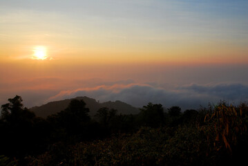 Landscape Tranquil scene of the sunrise with Orange sky and fog around the mountain in the morning at doi pha hom pok national park Thailand.