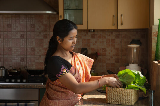 A young woman gets back her homegrown greens to the kitchen	