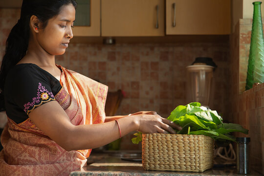 A young woman segregating her home grown vegetables in the kitchen	