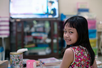 Asian little schoolgirl studying during her online lesson at home with her parent, social distance during quarantine,online education concept