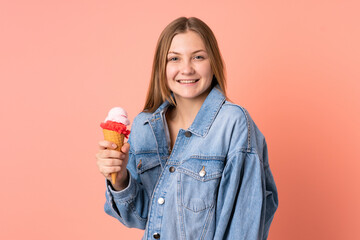 Teenager Ukrainian girl with a cornet ice cream isolated on pink background smiling a lot