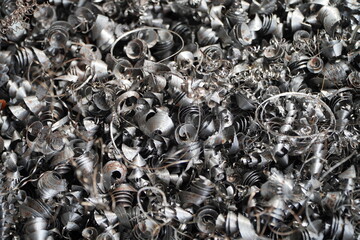 Steel scrap materials recycling. Aluminum chip waste after machining metal parts on a cnc lathe. Closeup twisted spiral steel shavings. Small roughness sharpness,